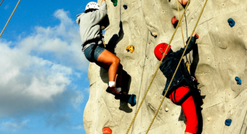 School children climbing rock wall on residential